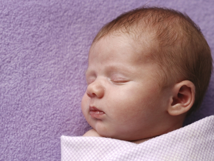 baby swaddled in pink cloth laying