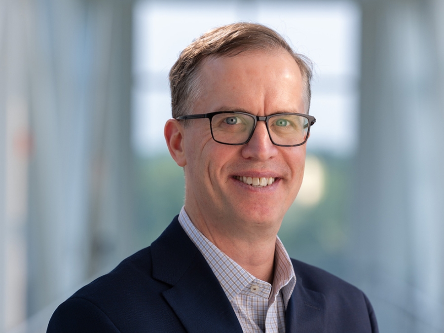David Miller wearing glasses and blue jacket smiling  