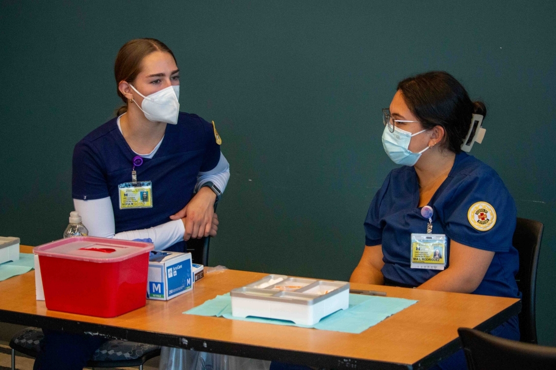 Two flu clinic workers talk at the table